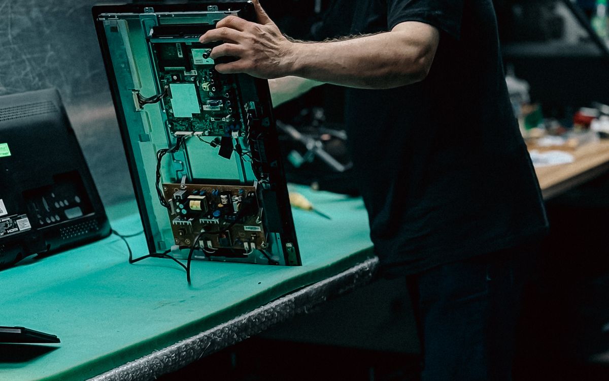 Technician repairing the panel of an opened flat-screen television
