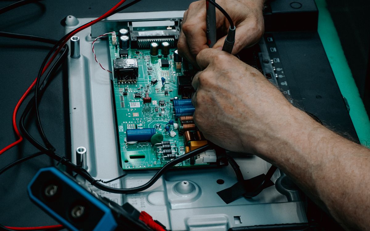 Close-up of a technician repairing a television circuit board